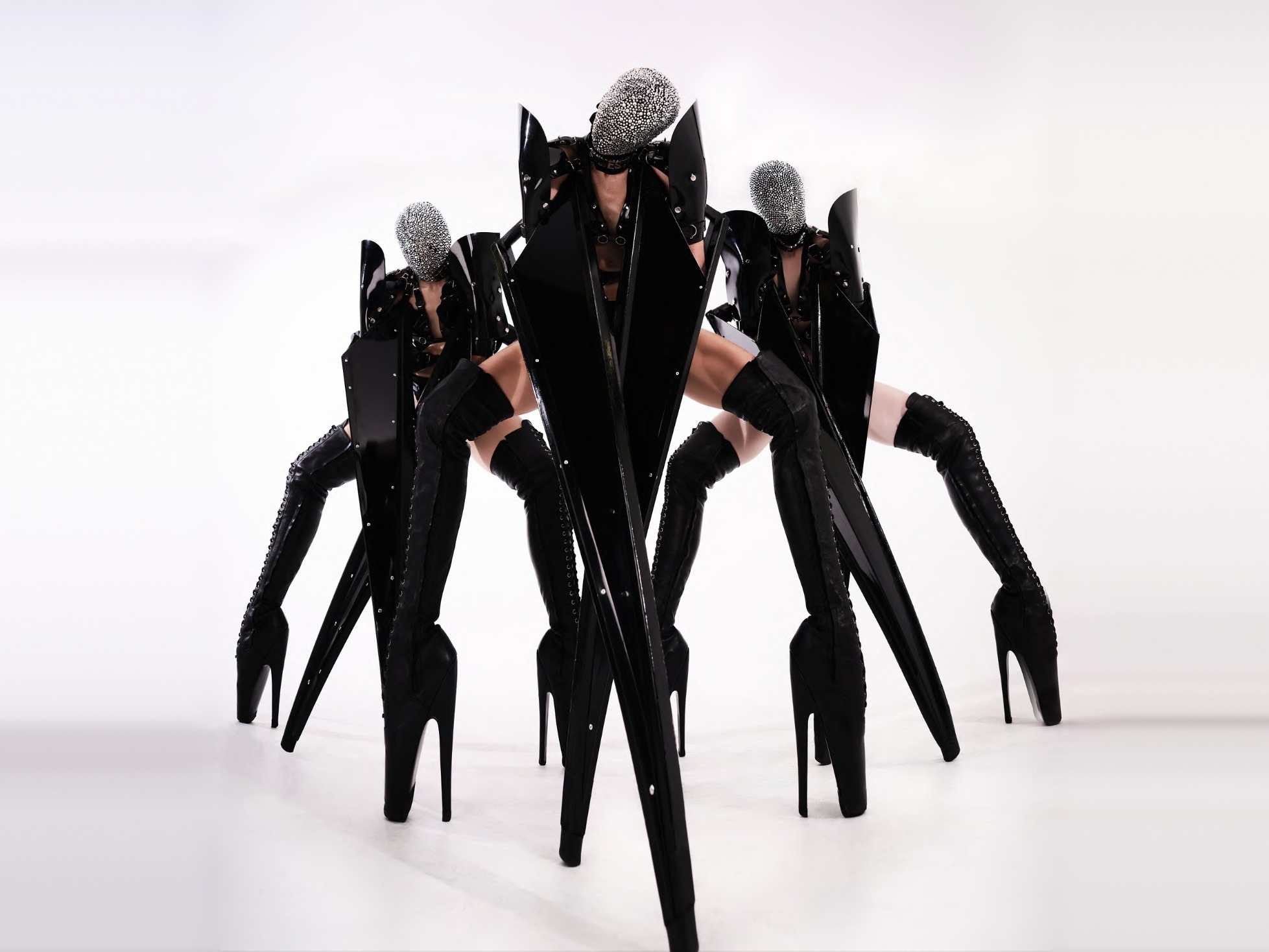 Three masked four-legged monsters in black couture armour and crystal masks
