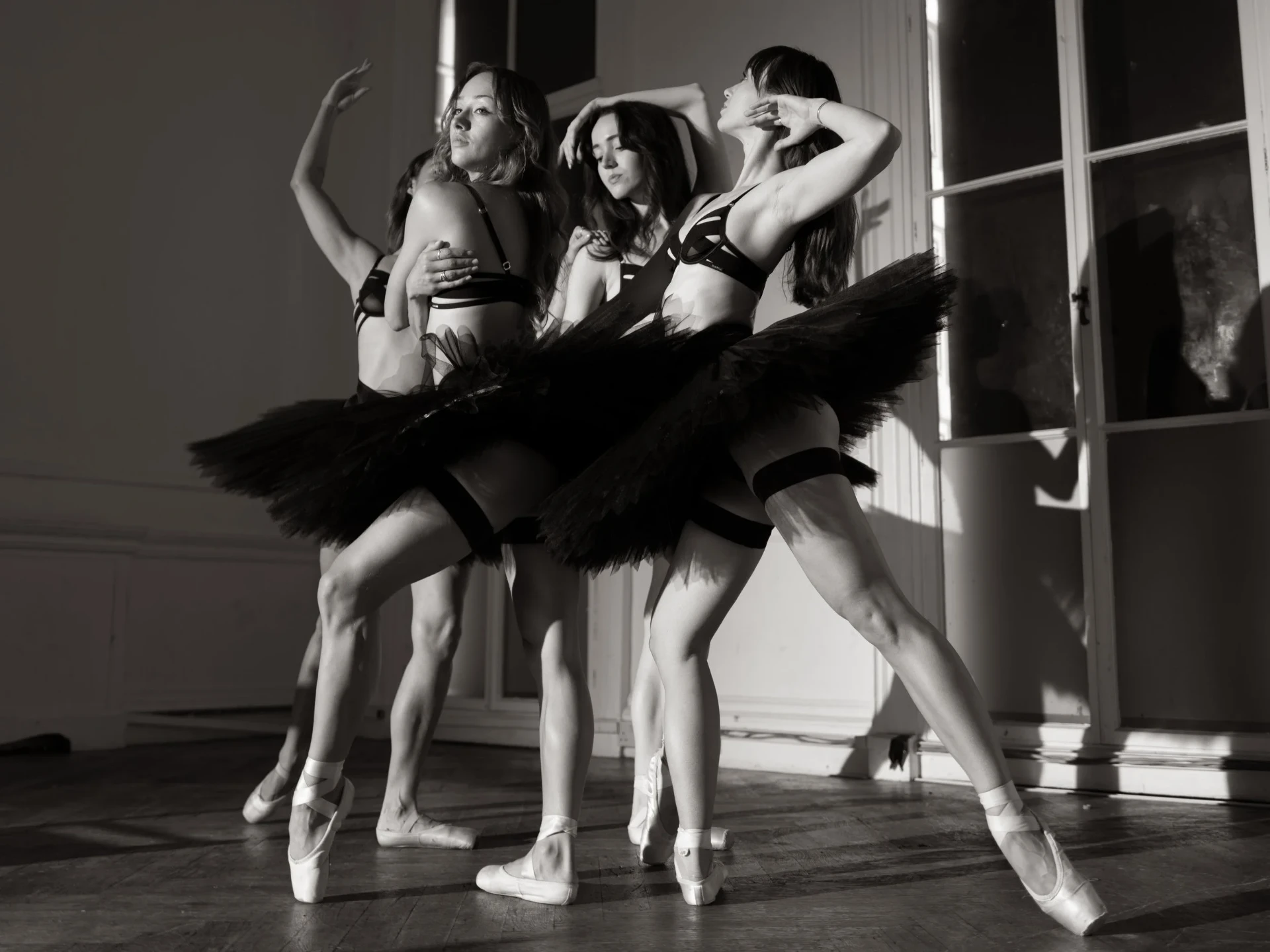 Four ballet performers in black tutus and pointe shoes